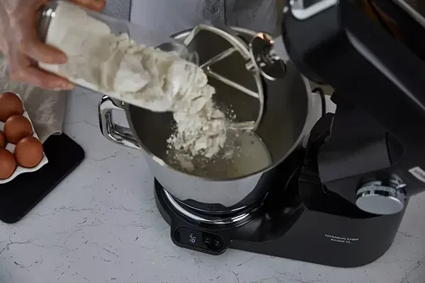 Oberansicht der Kenwood Titanium Chef Baker XL. Es wird Mehl in die Schüssel hineingegeben