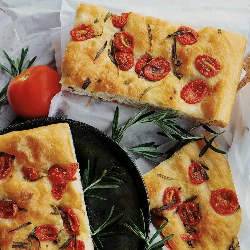 frisch gebackene Focaccia mit Rosmarin, Tomaten und Olivenöl auf einem Teller